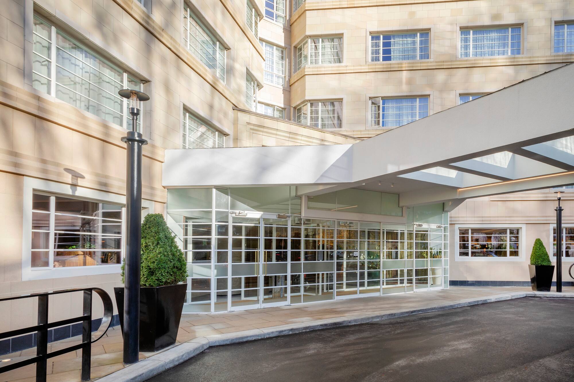 Hotel entrance with glass doors, white canopy, and light stone facade.