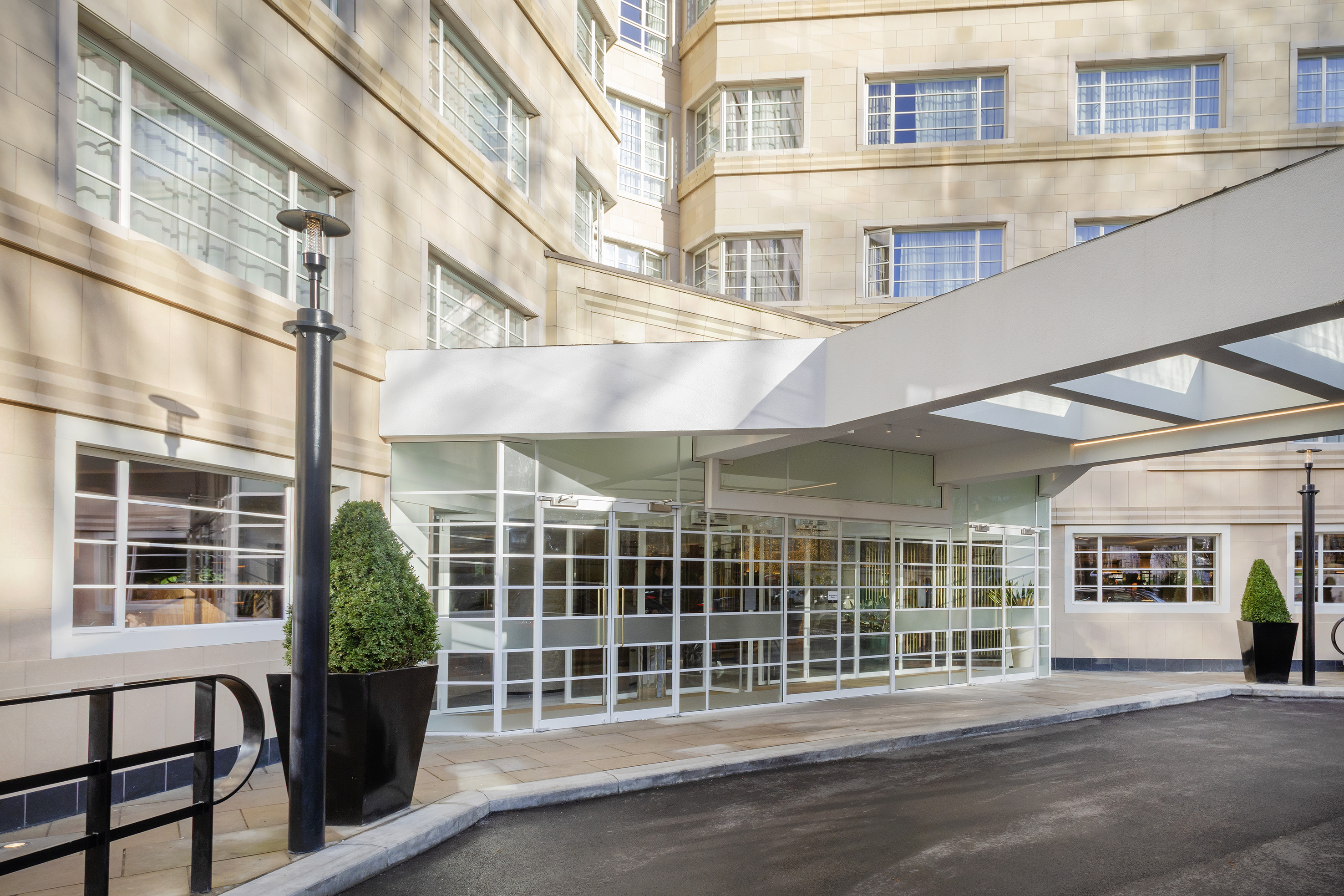 Hotel entrance with glass doors, white canopy, and light stone facade.
