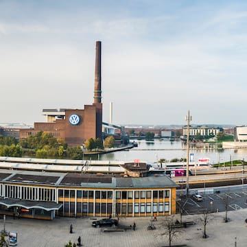 a large building with a tall chimney and a river