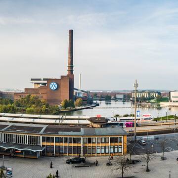 a large building with a tall chimney and a river