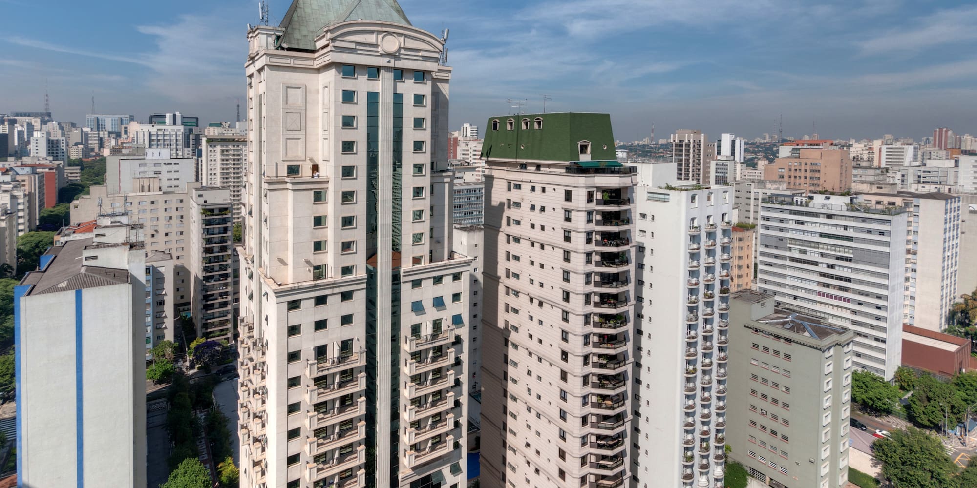 a tall buildings with trees and a blue sky
