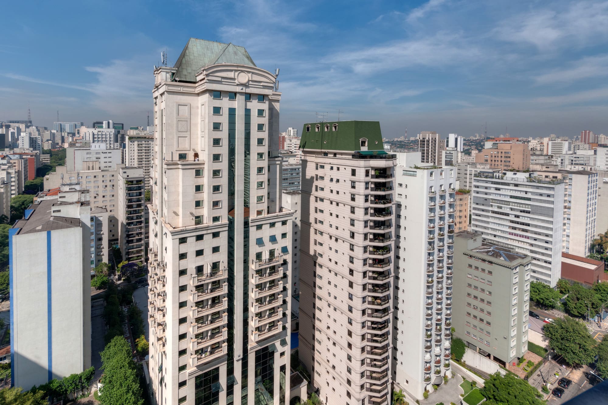 Modern high-rise city skyline with two prominent buildings featuring green roofs.