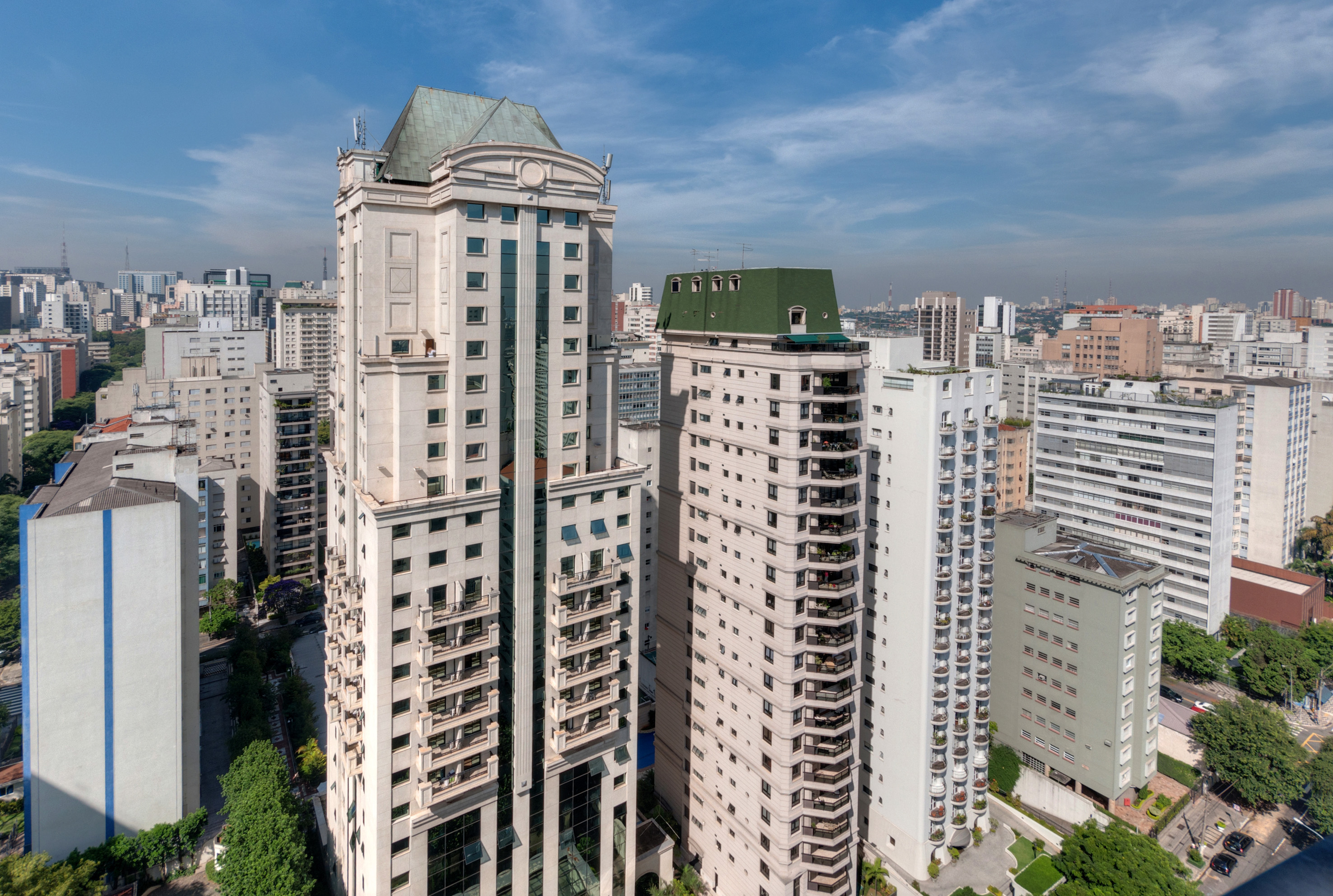 Modern high-rise city skyline with two prominent buildings featuring green roofs.