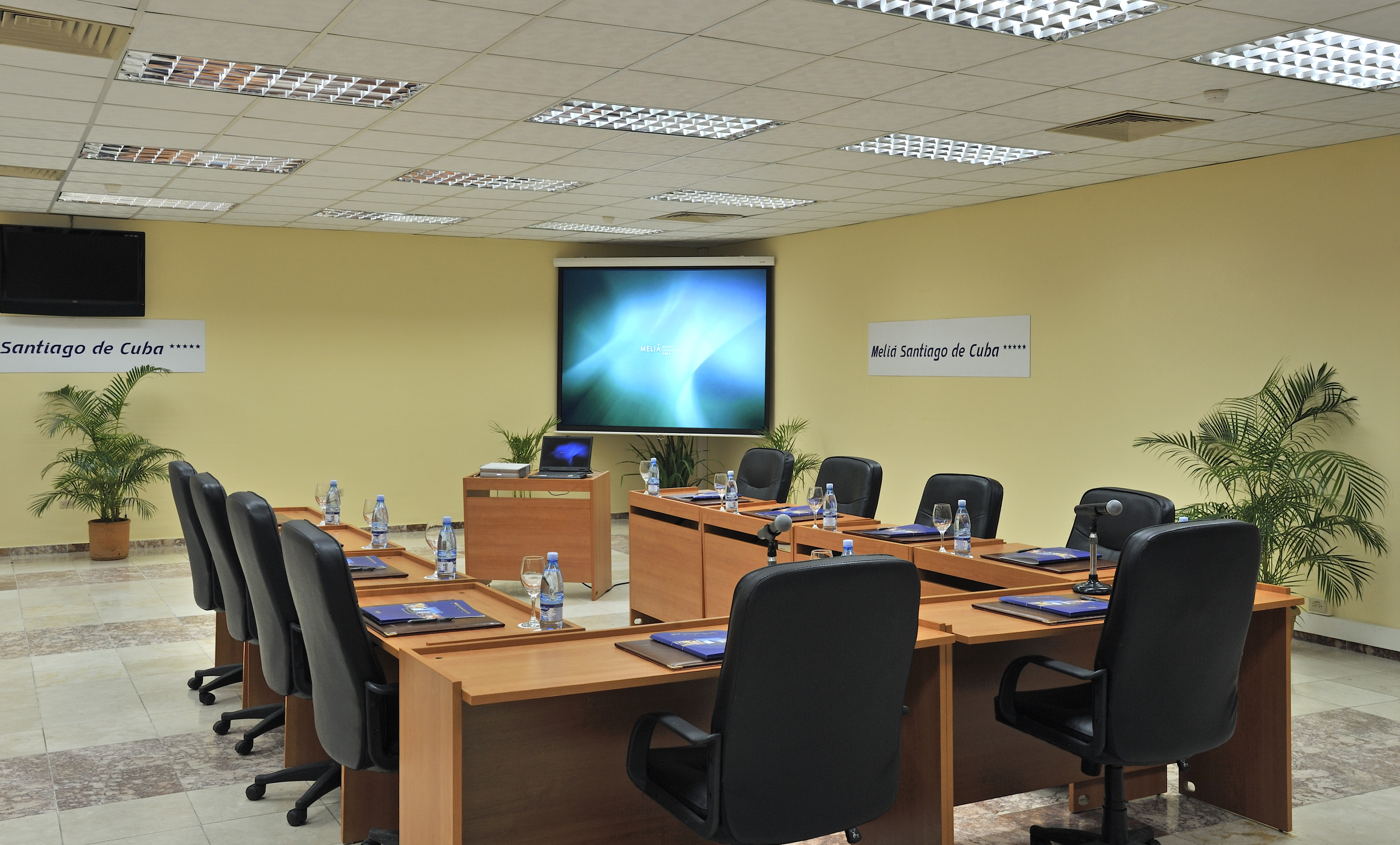 a room with a large screen and tables