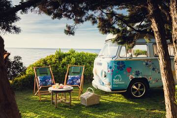 a van and chairs on grass by the water