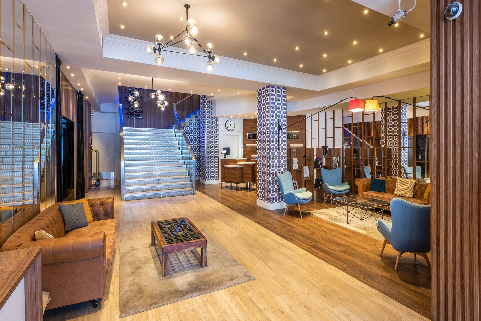 Modern hotel lobby with reception desk, lounge area, and illuminated staircase.