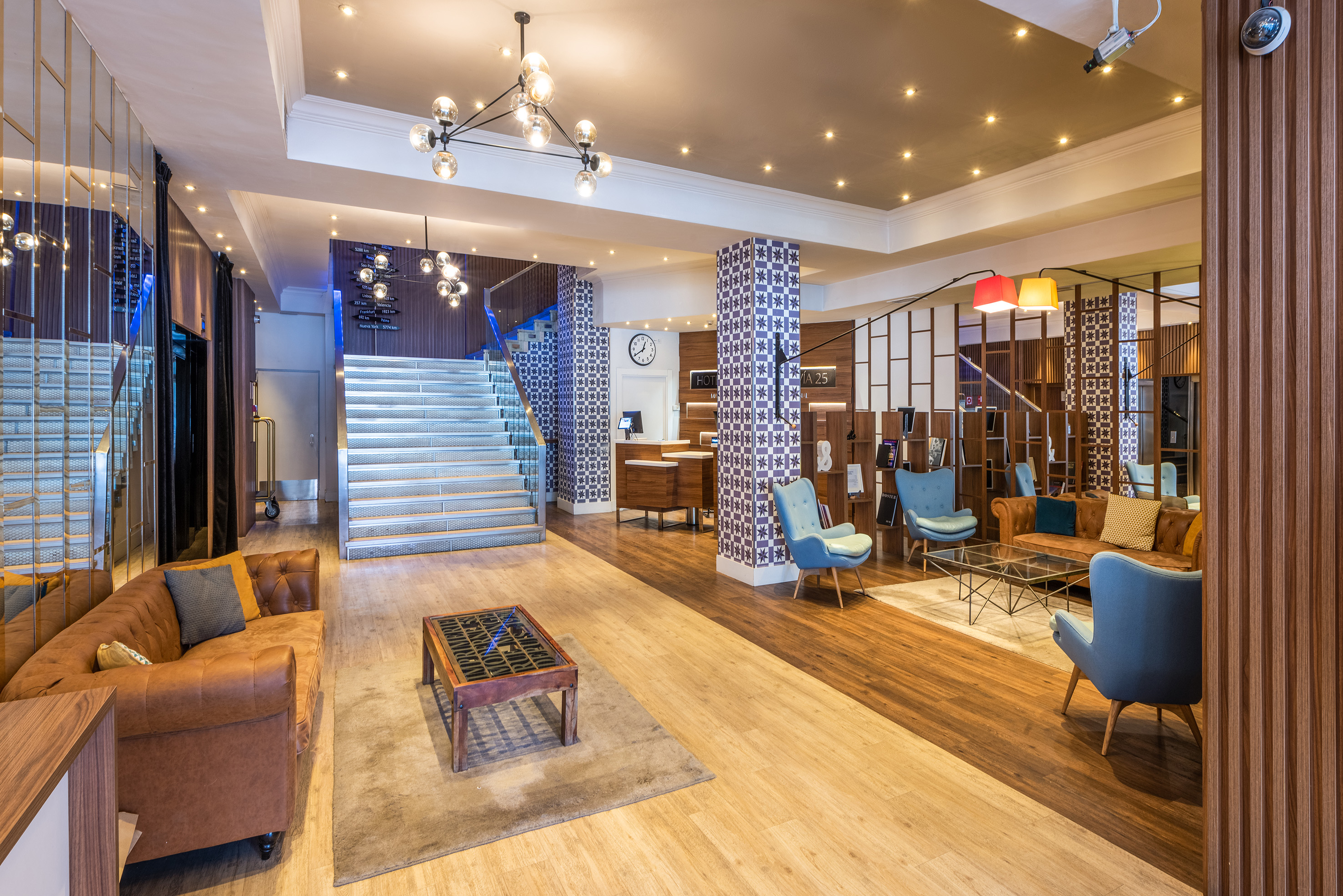 Modern hotel lobby with reception desk, lounge area, and illuminated staircase.