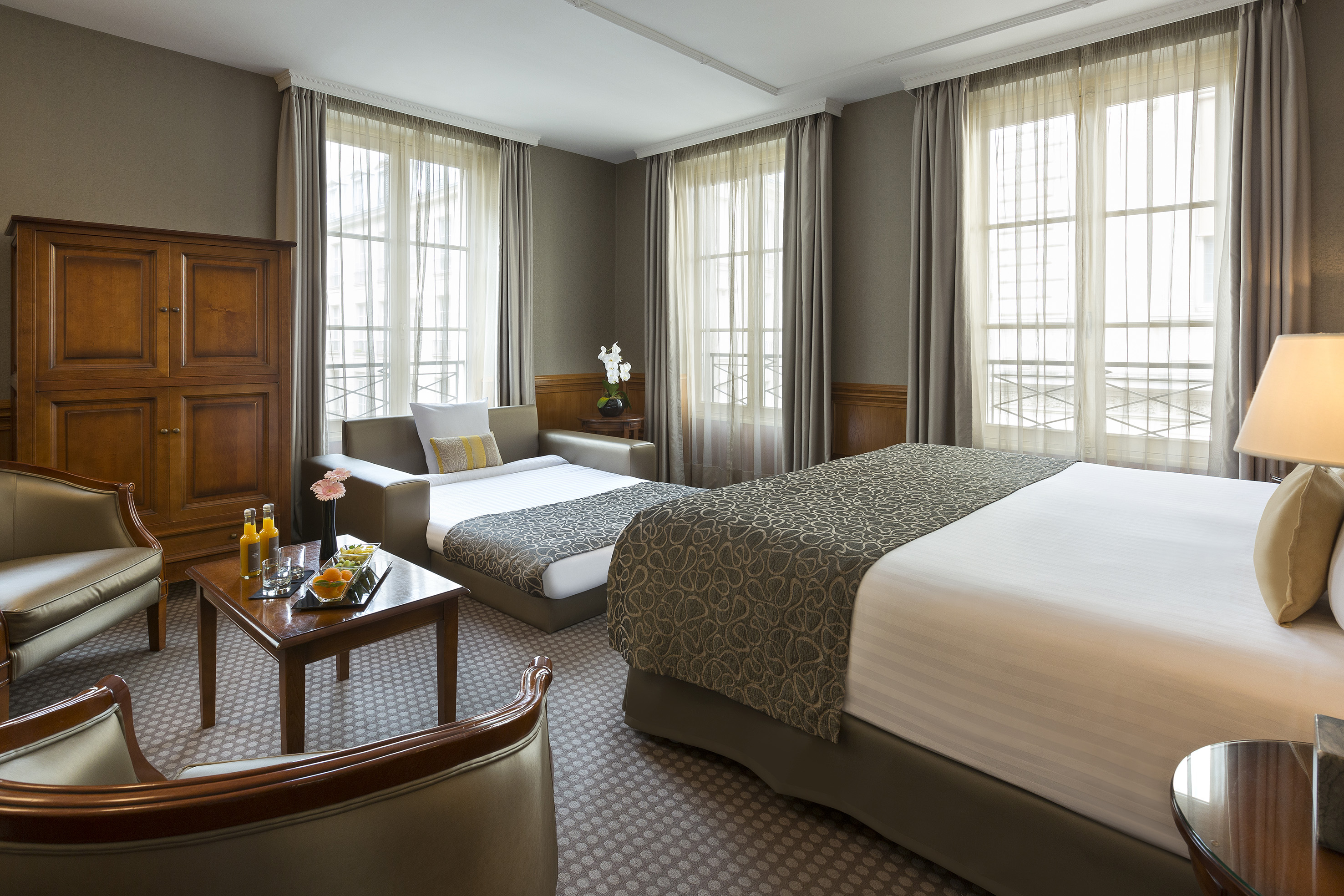 Hotel suite with large bed, pull-out sofa, and traditional wood furnishings.