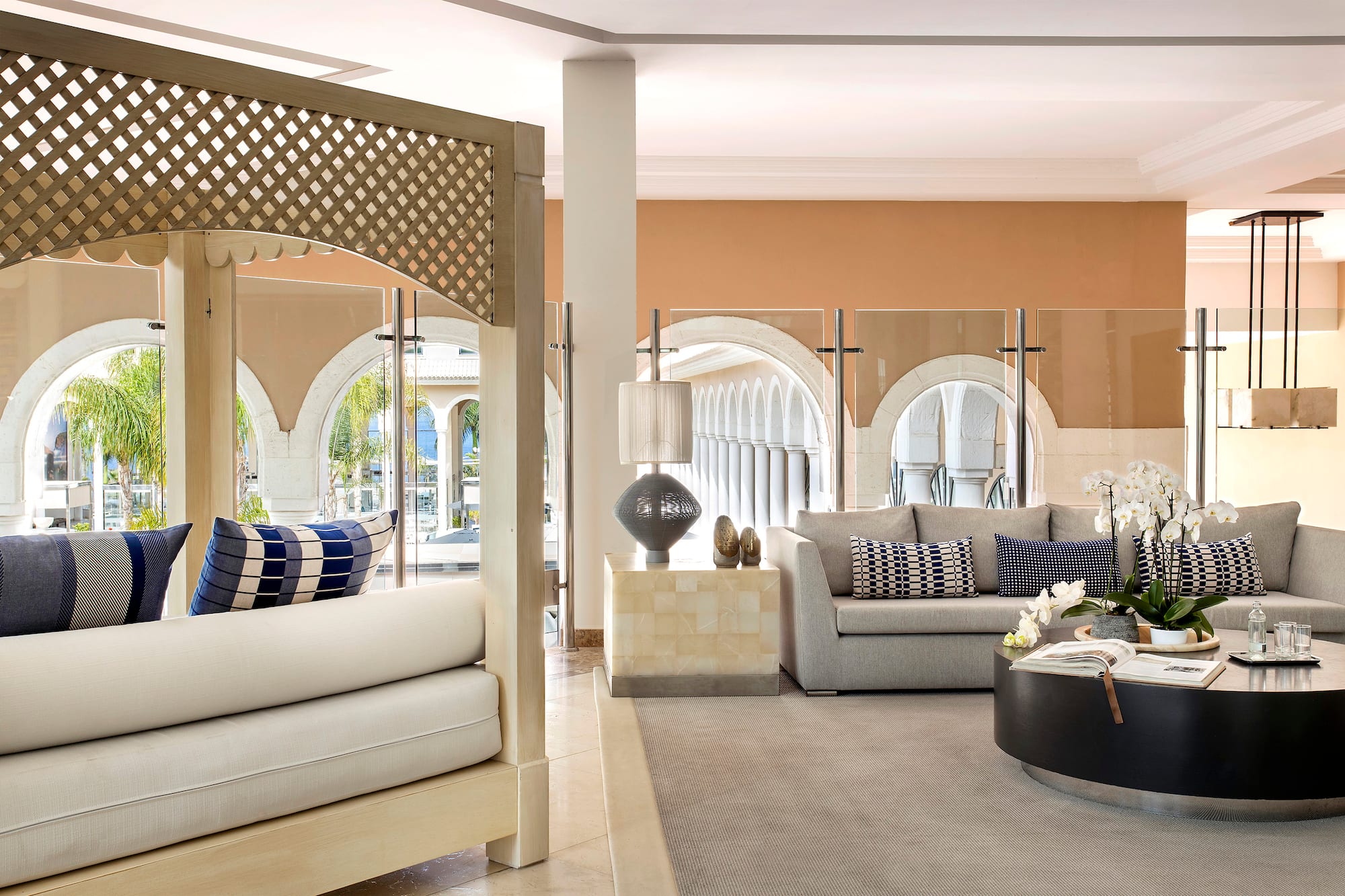 Modern hotel lounge with gray sofa, coffee table, orchids, and outdoor arches.