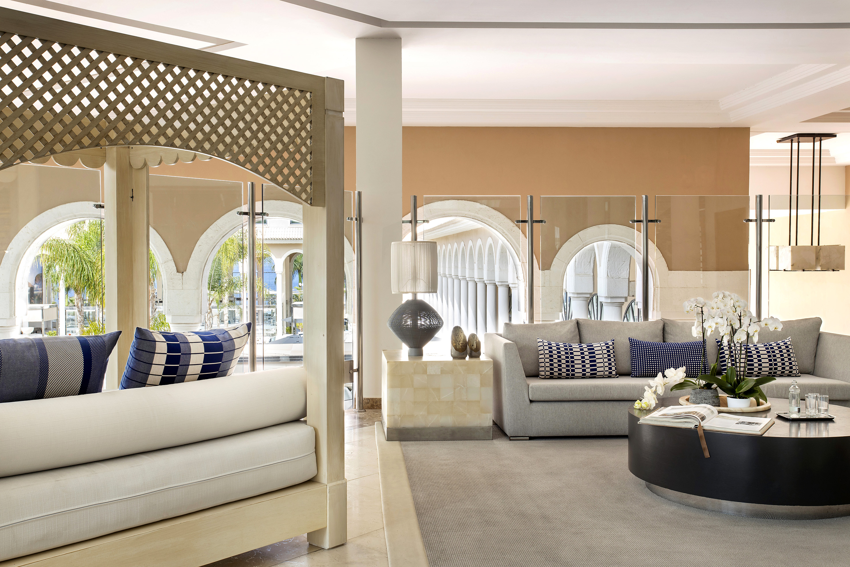Modern hotel lounge with gray sofa, coffee table, orchids, and outdoor arches.