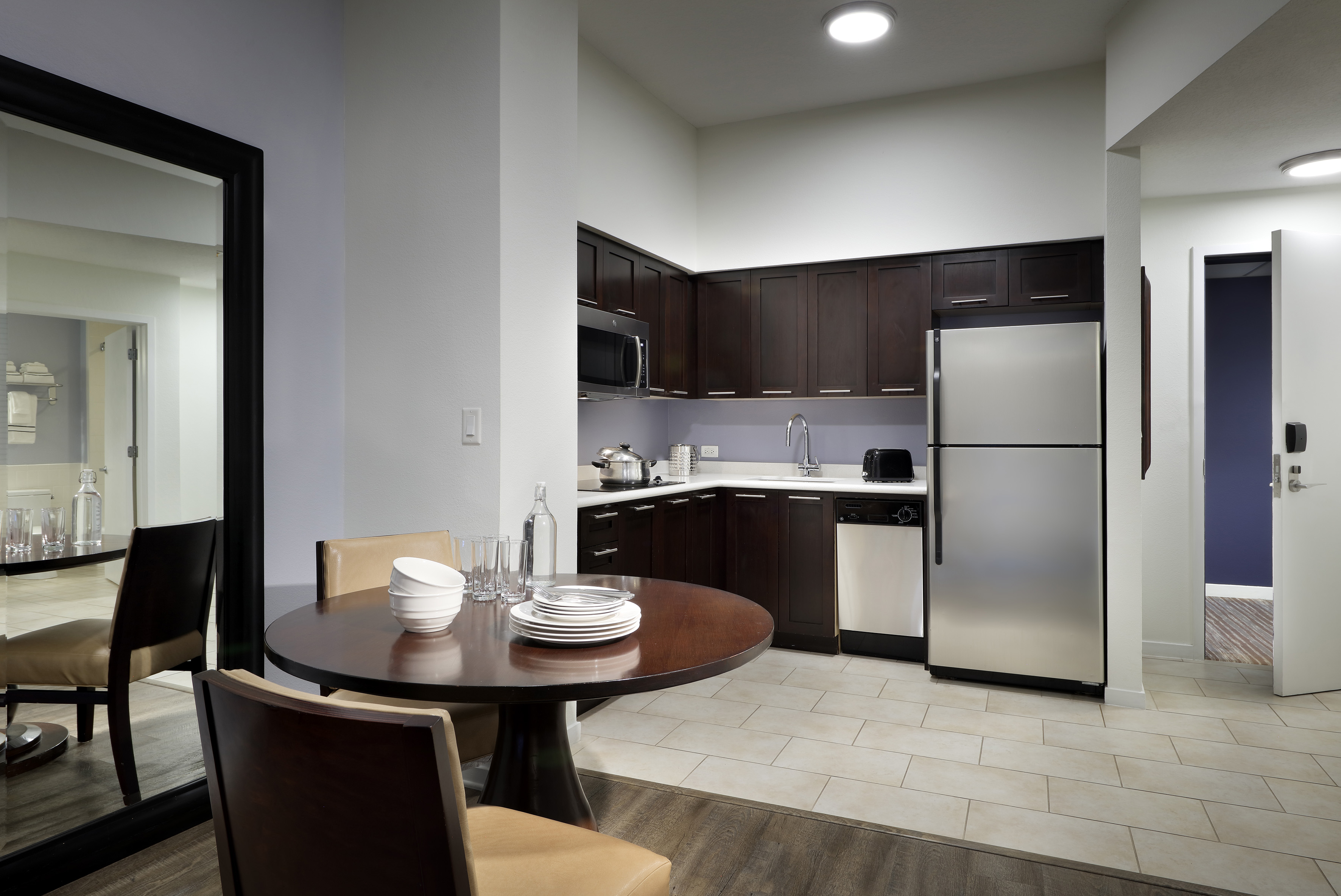 Modern kitchen dining area with dark cabinets, stainless steel appliances.