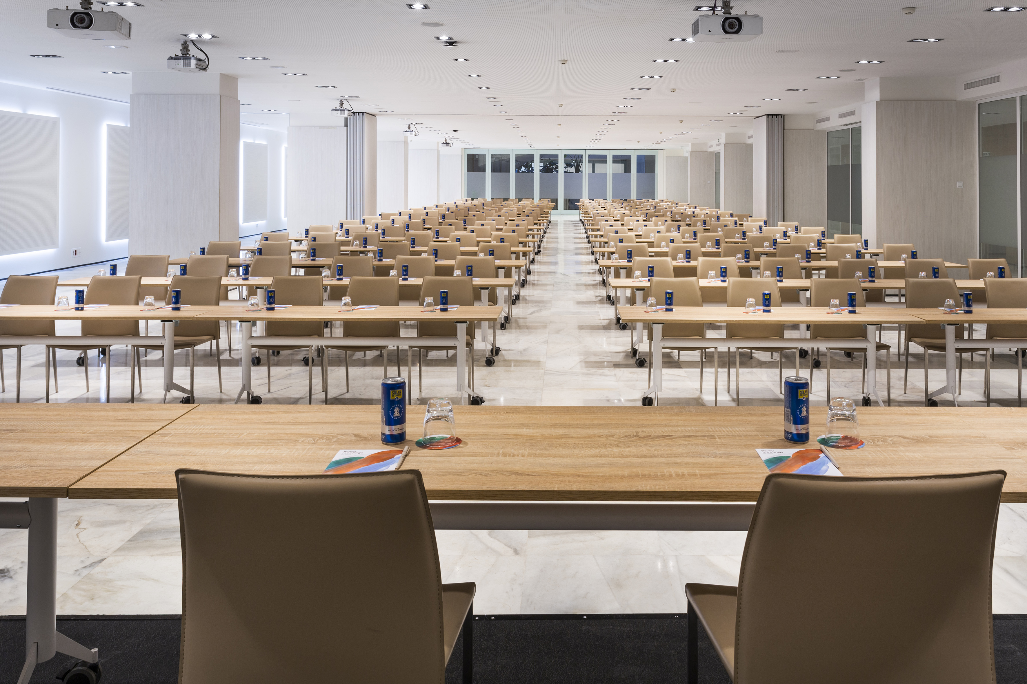 Empty modern conference room with tables, beige chairs, and projectors.
