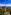 a tower on a hill with trees and a city in the background