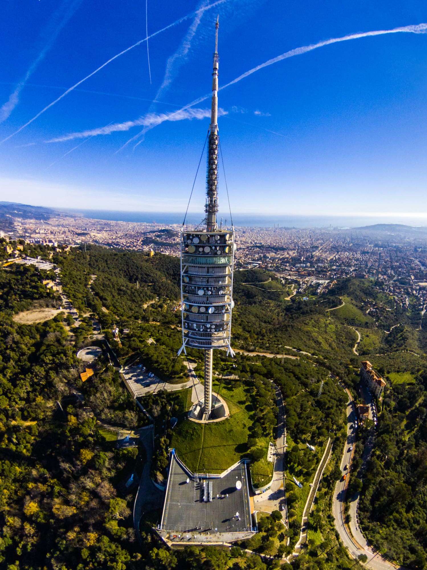 a tower on a hill with trees and a city in the background