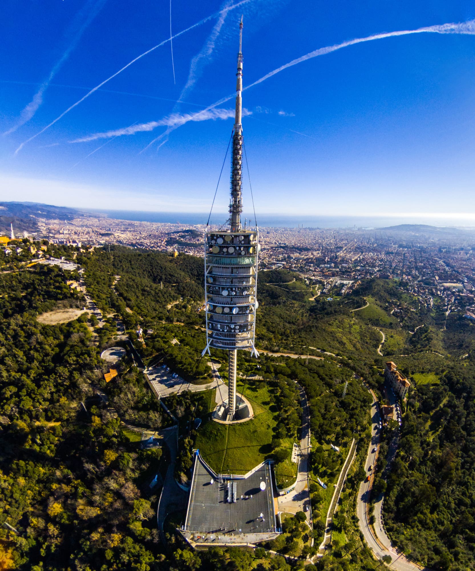 a tower on a hill with trees and a city in the background