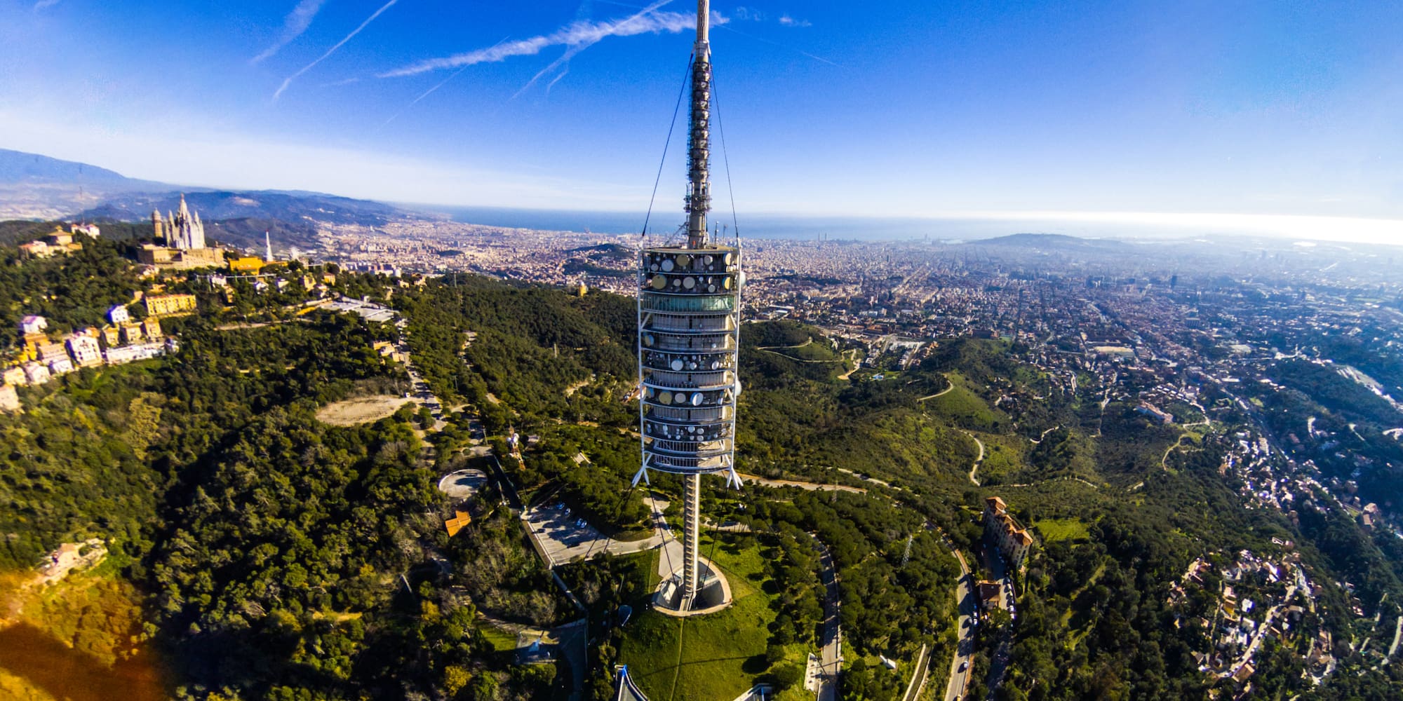 a tower on a hill with trees and a city in the background