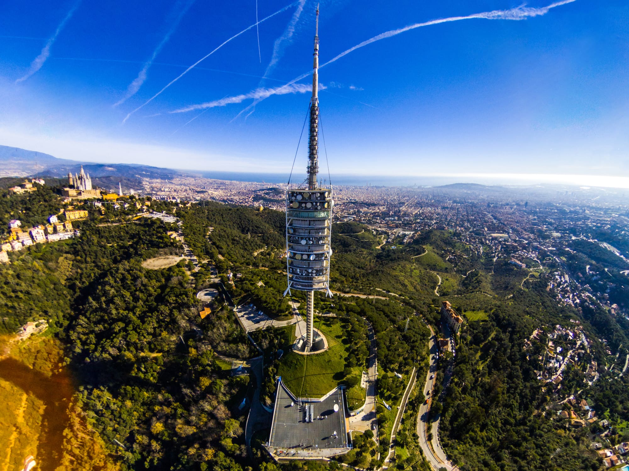 a tower on a hill with trees and a city in the background