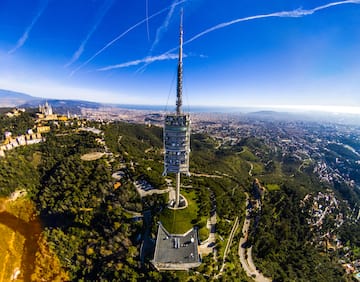 a tower on a hill with trees and a city in the background