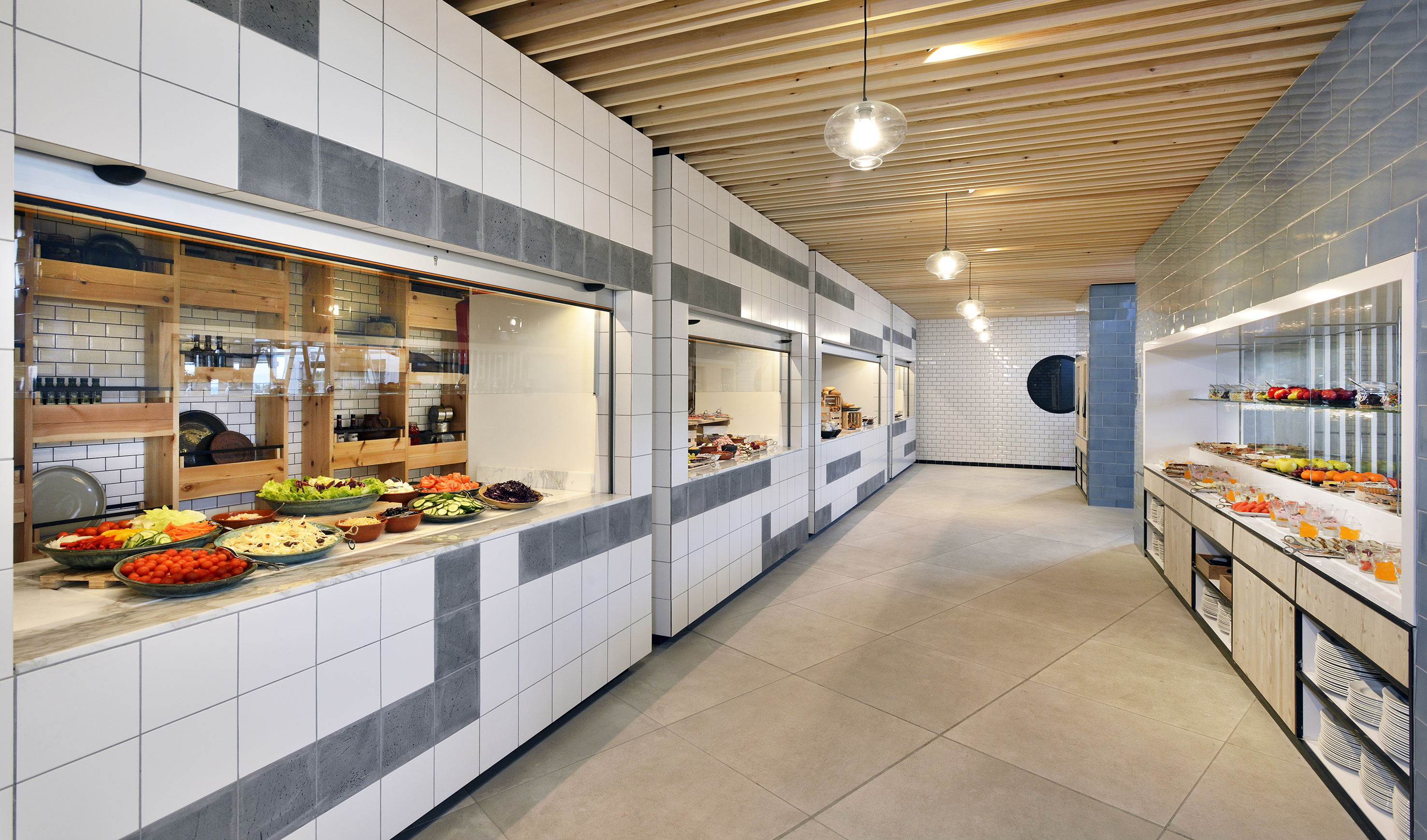 Modern buffet line with fresh salads, fruits, and various prepared dishes.
