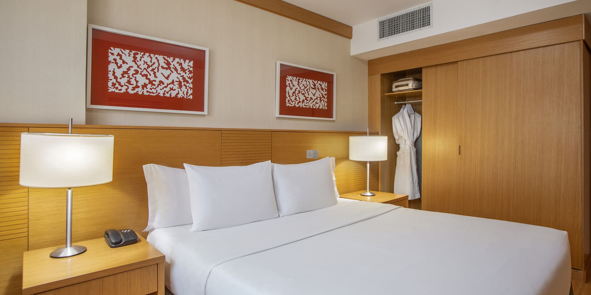 a bed with white sheets and a white robe on the wall