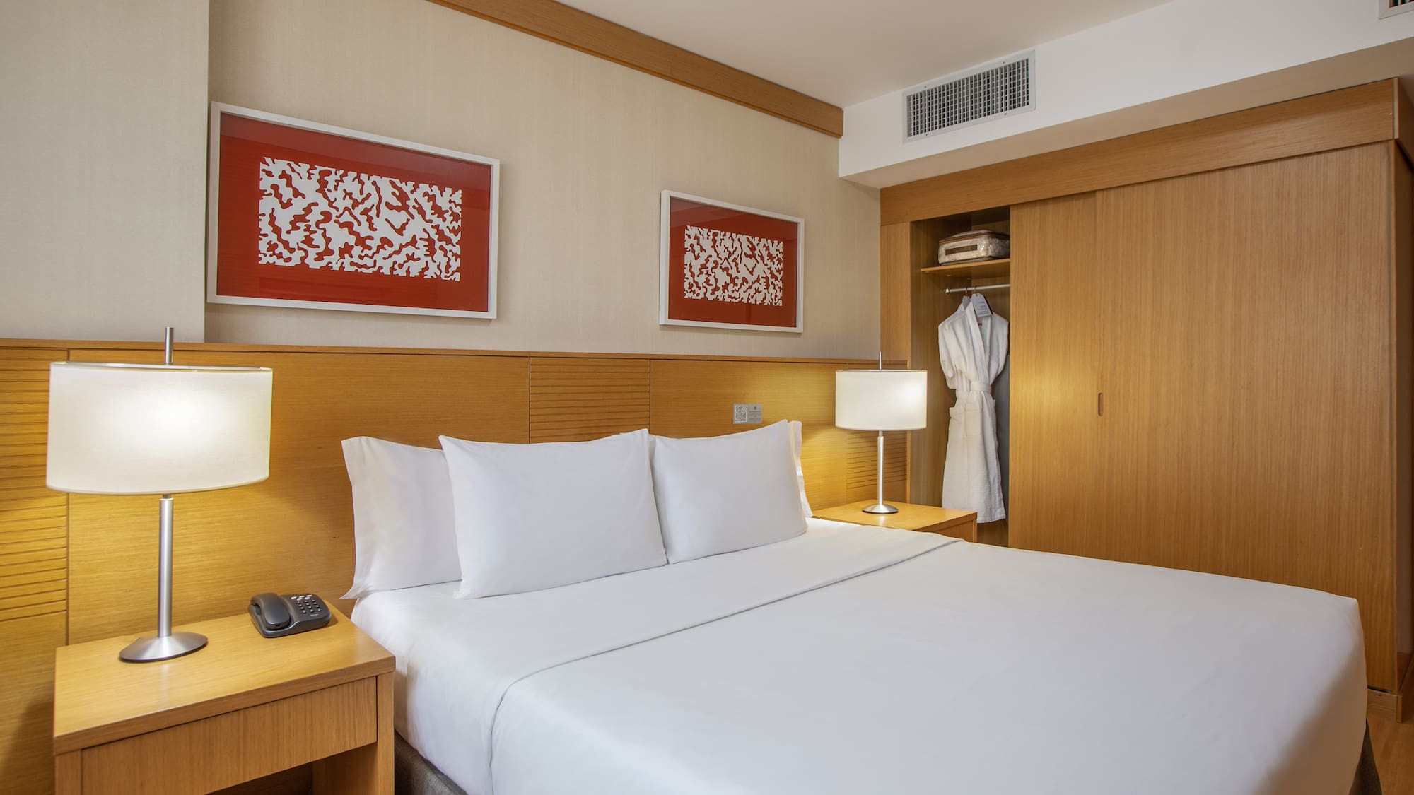 a bed with white sheets and a white robe on the wall