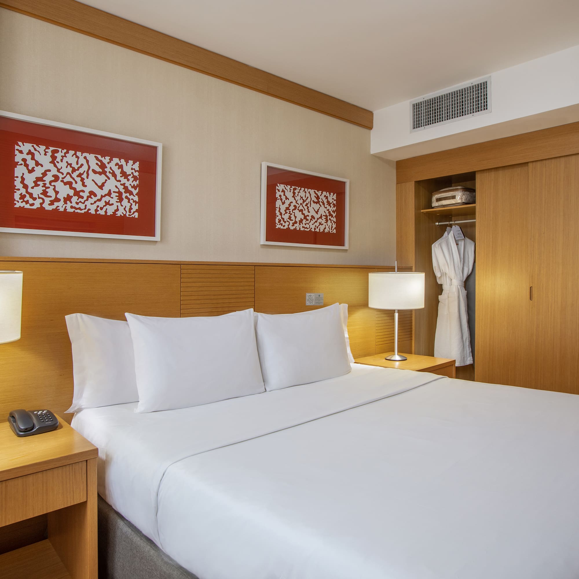 a bed with white sheets and a white robe on the wall