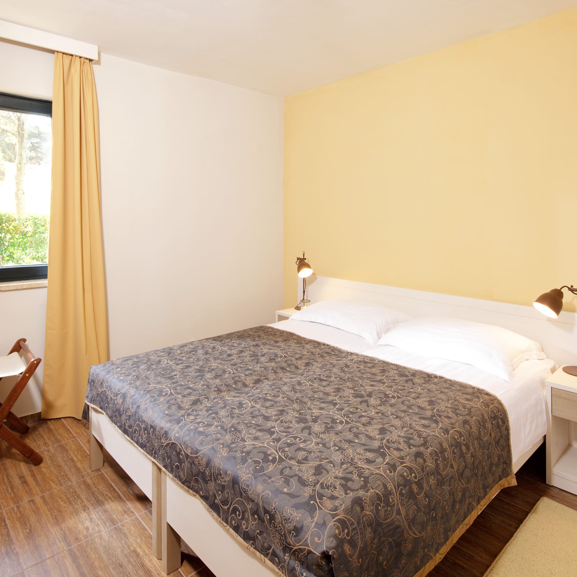 a bed with two lamps and a chair in a room