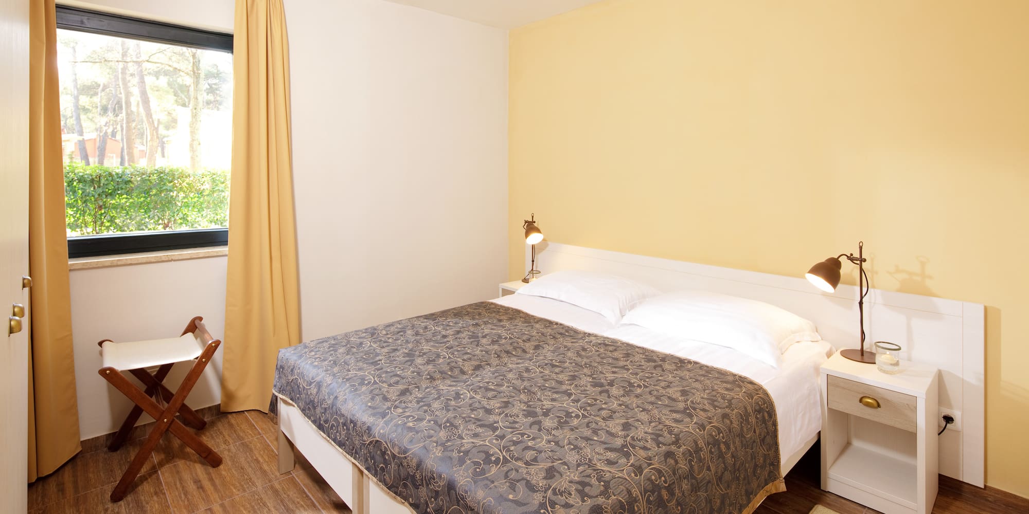 a bed with two lamps and a chair in a room