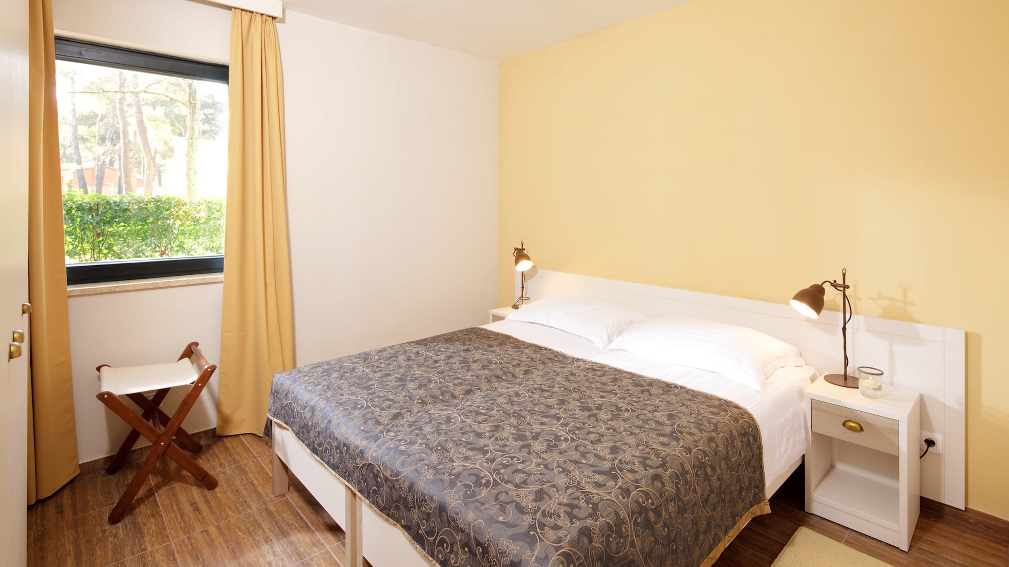 a bed with two lamps and a chair in a room