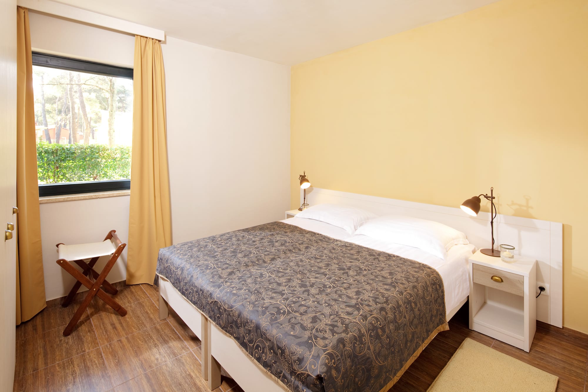 a bed with two lamps and a chair in a room