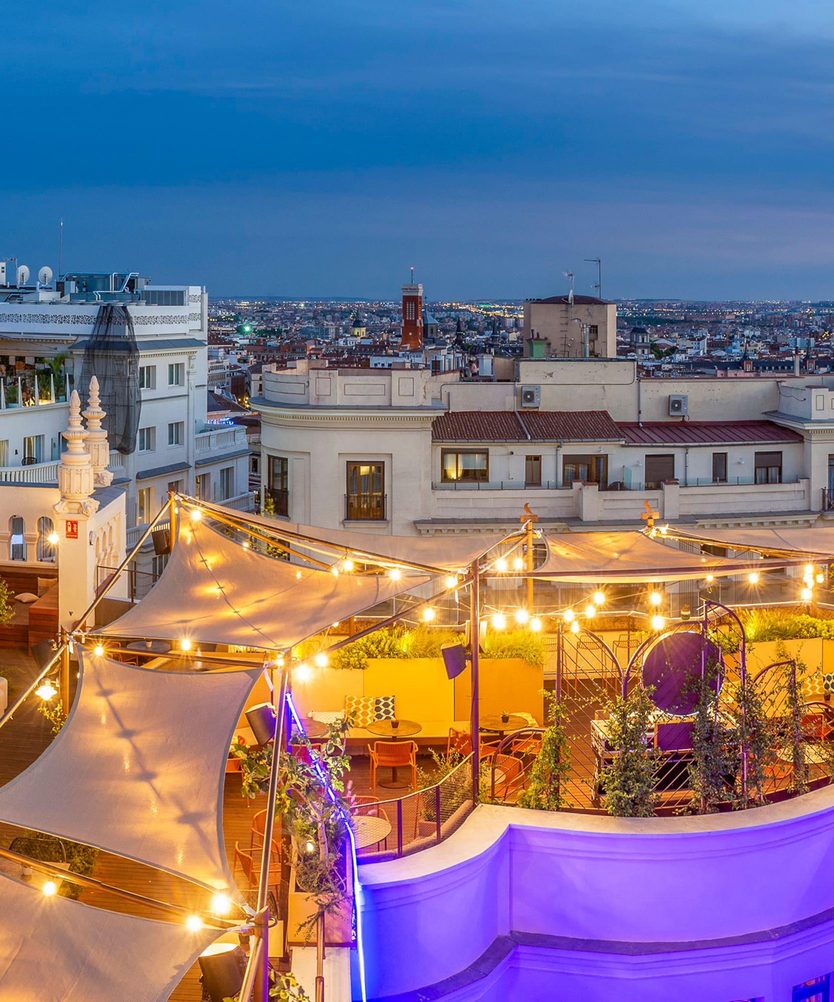 a rooftop patio with lights and a city in the background