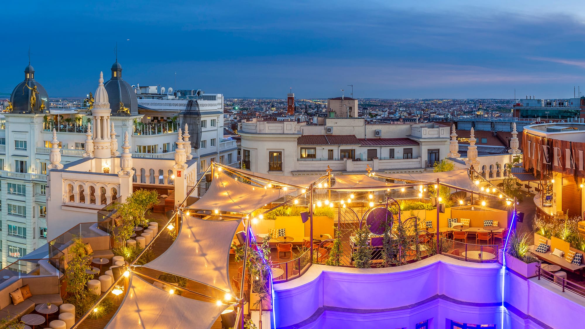 a rooftop patio with lights and a city in the background