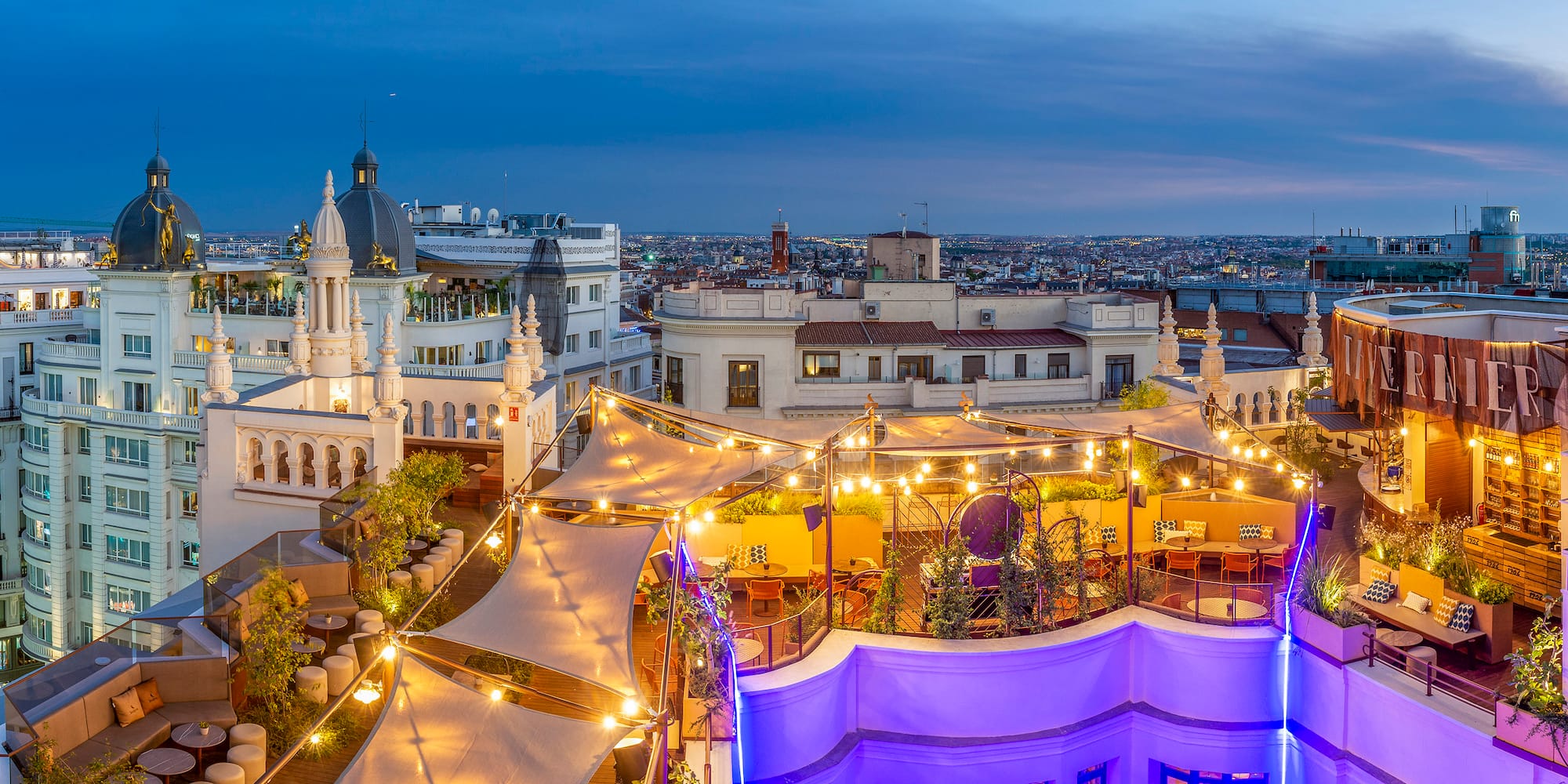 a rooftop patio with lights and a city in the background
