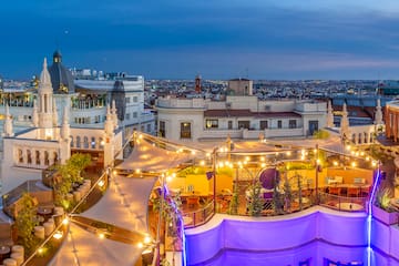 a rooftop patio with lights and a city in the background
