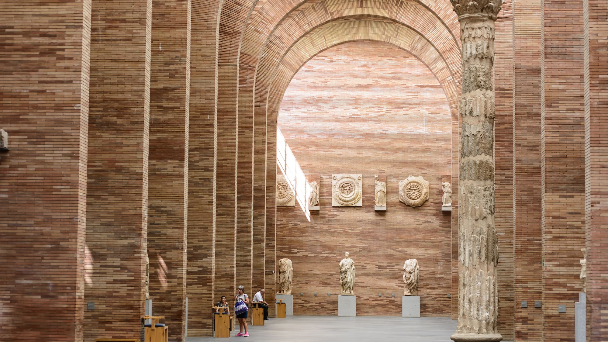 a group of people in a room with columns and statues