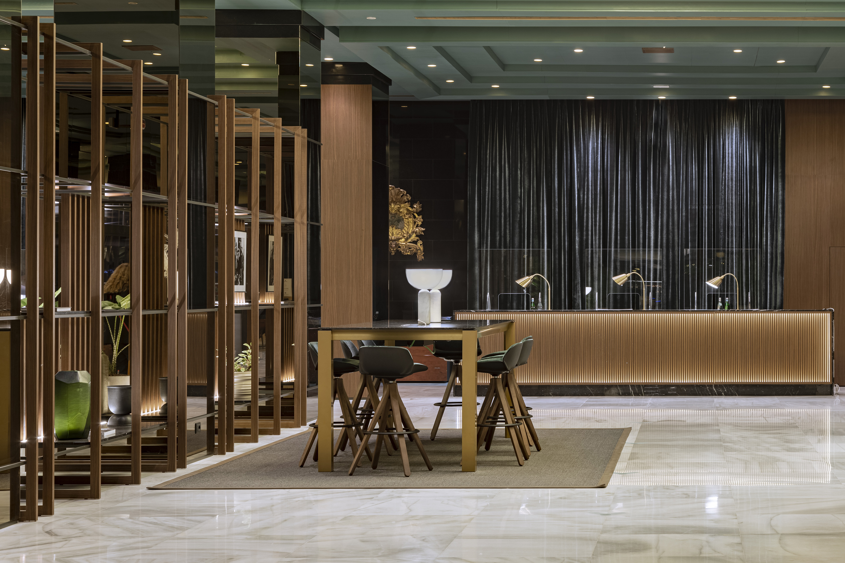 Modern hotel lobby with marble floor, wooden screen, and illuminated reception desk.