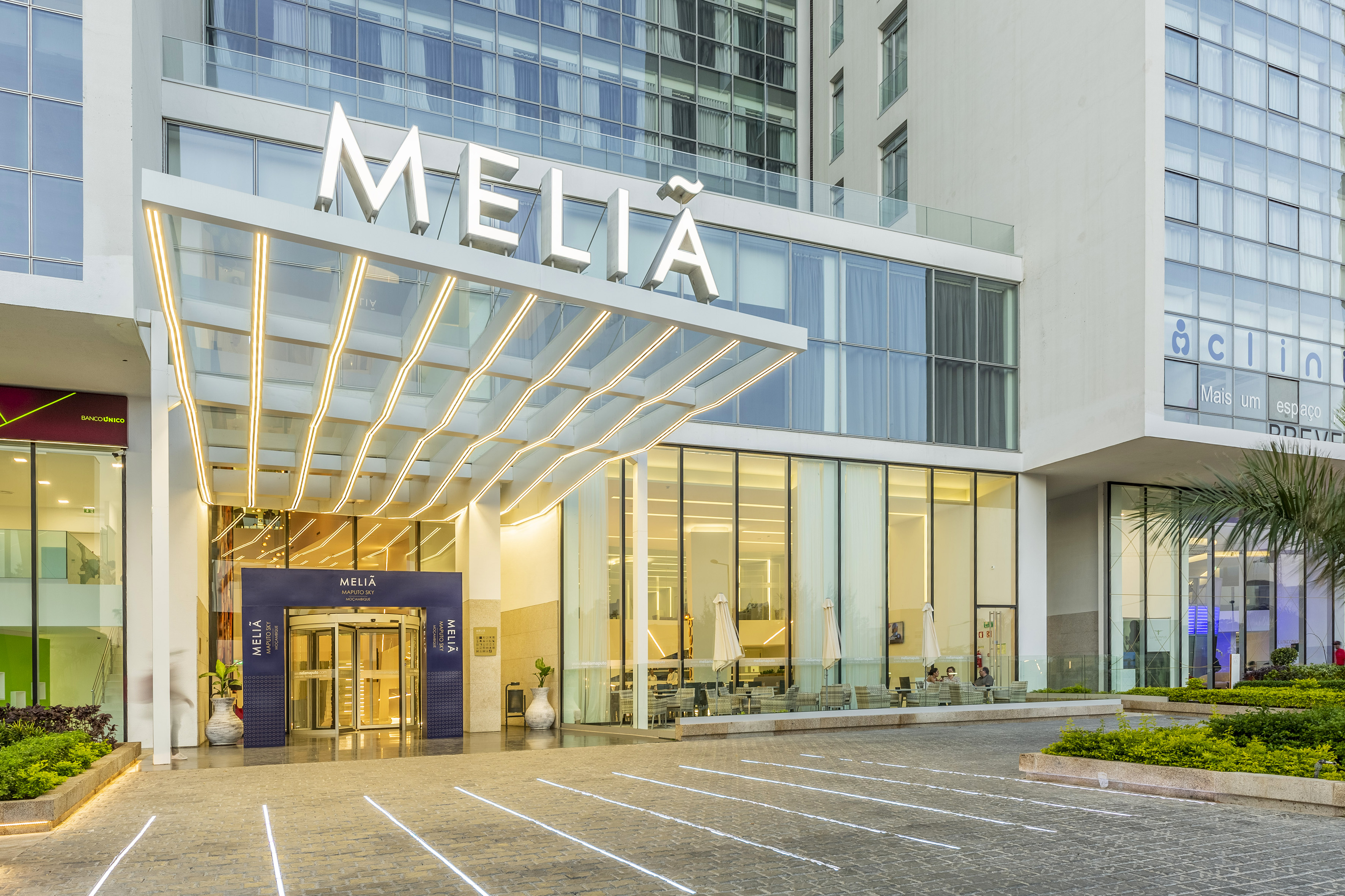 Meliá Maputo Sky hotel entrance, modern glass facade with illuminated canopy.