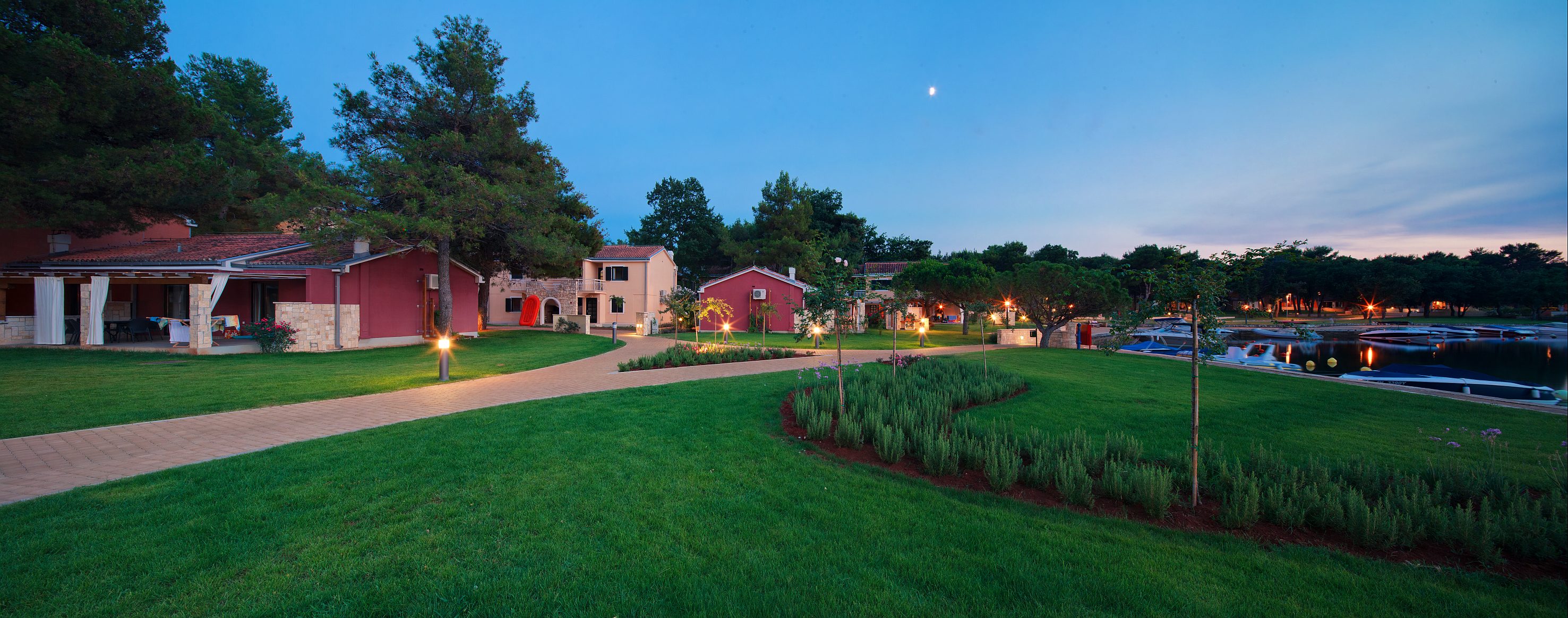 a lawn with trees and houses in the background