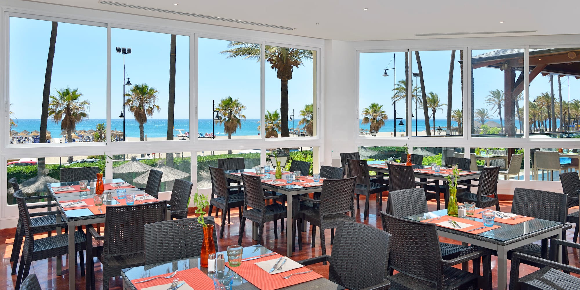 a room with tables and chairs and a view of the ocean