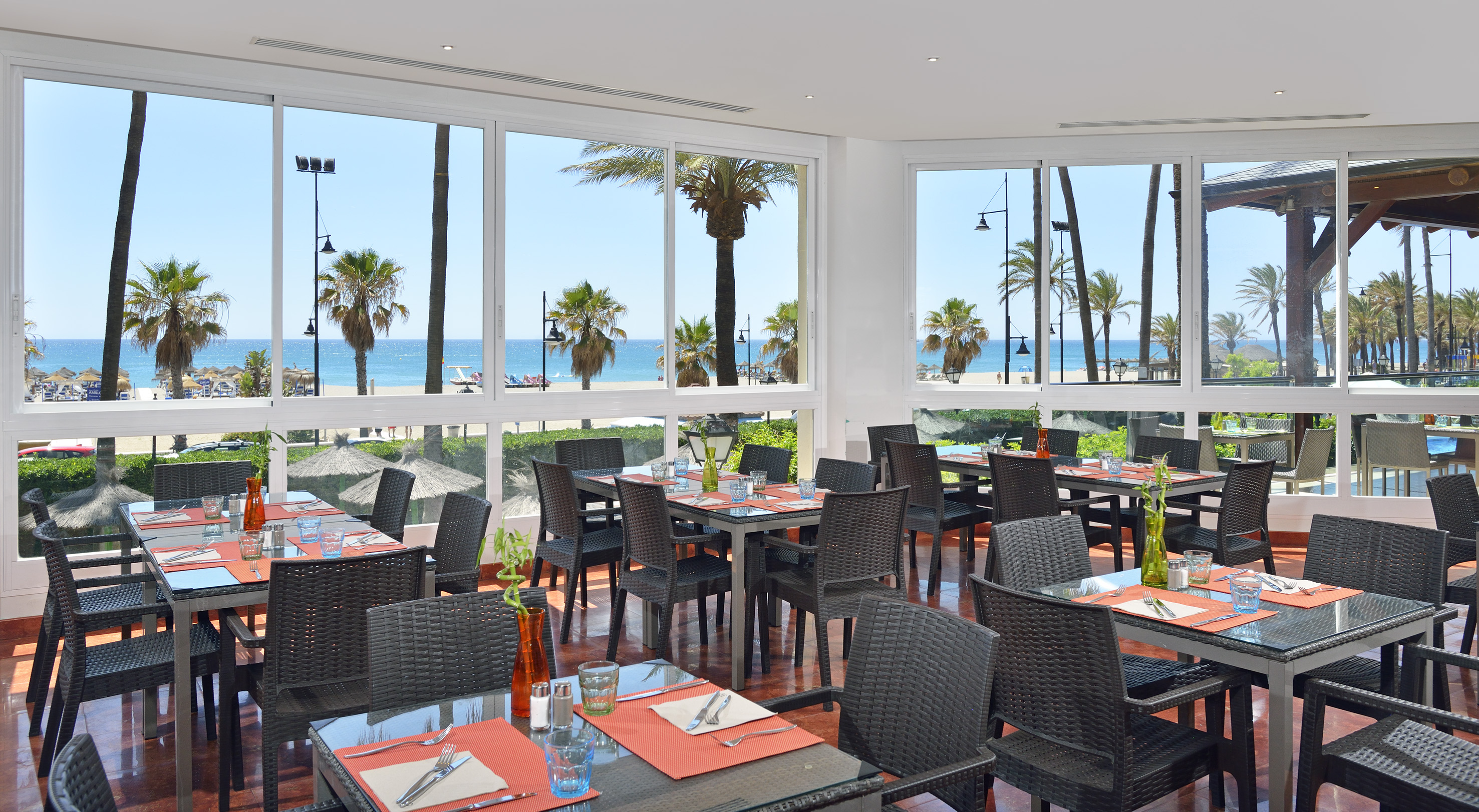 a room with tables and chairs and a view of the ocean