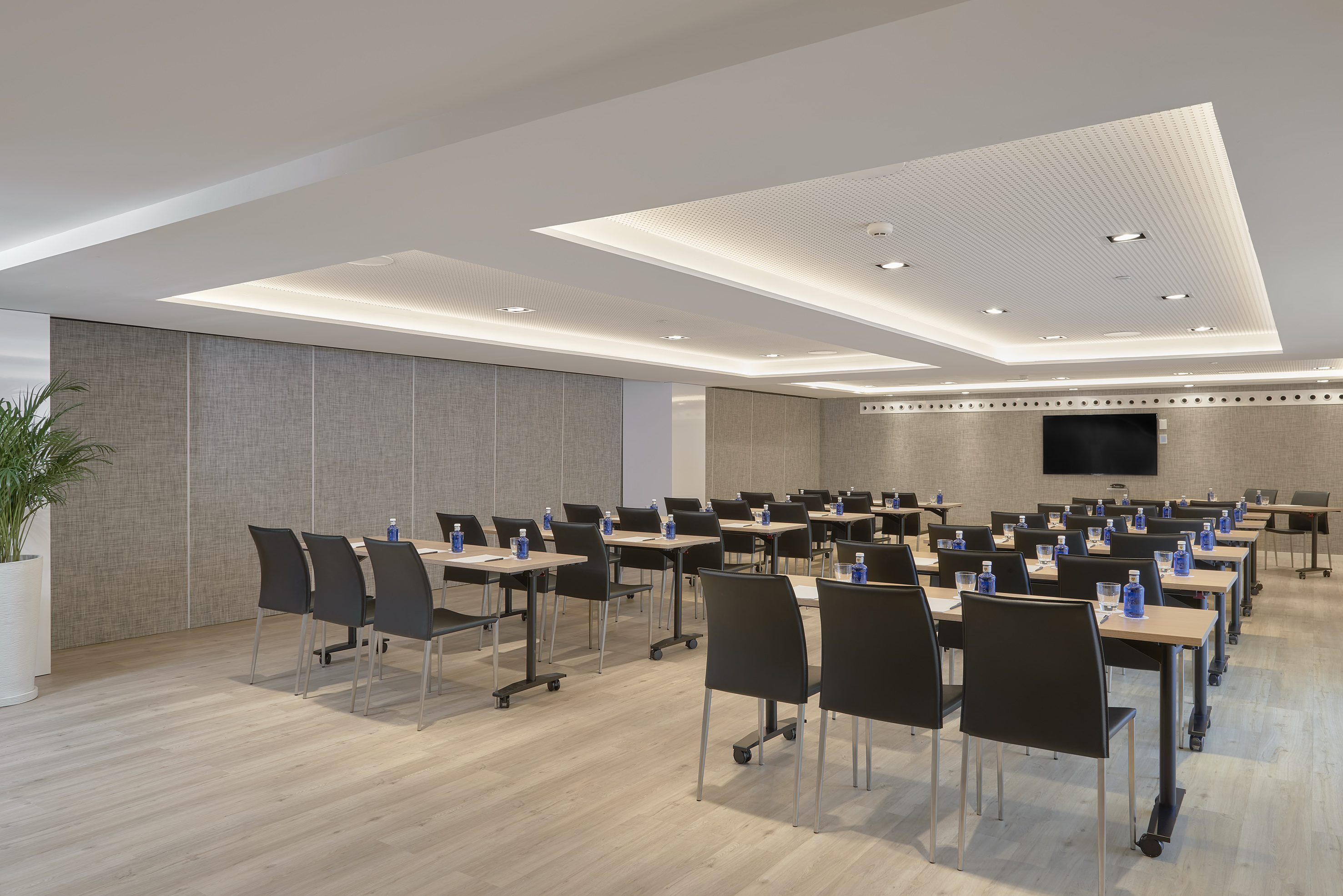 Modern conference room with individual desks, chairs, and a large display.