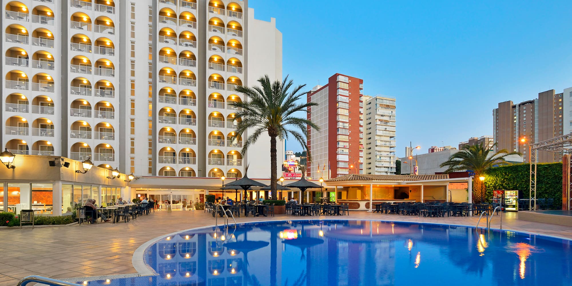 a pool with tables and chairs in front of a building