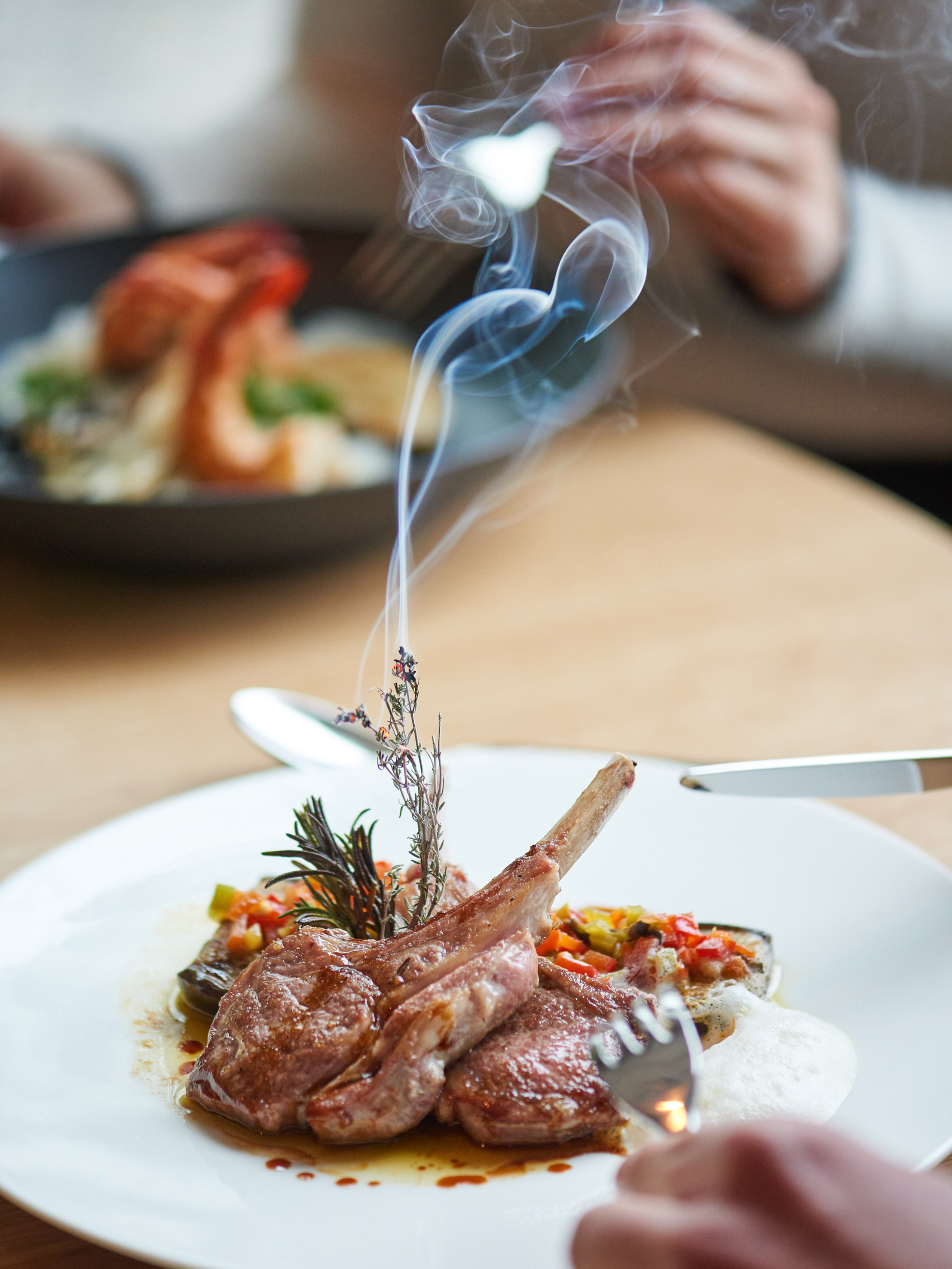 Smoked lamb chops with herbs and vegetables on a plate, fine dining meal.