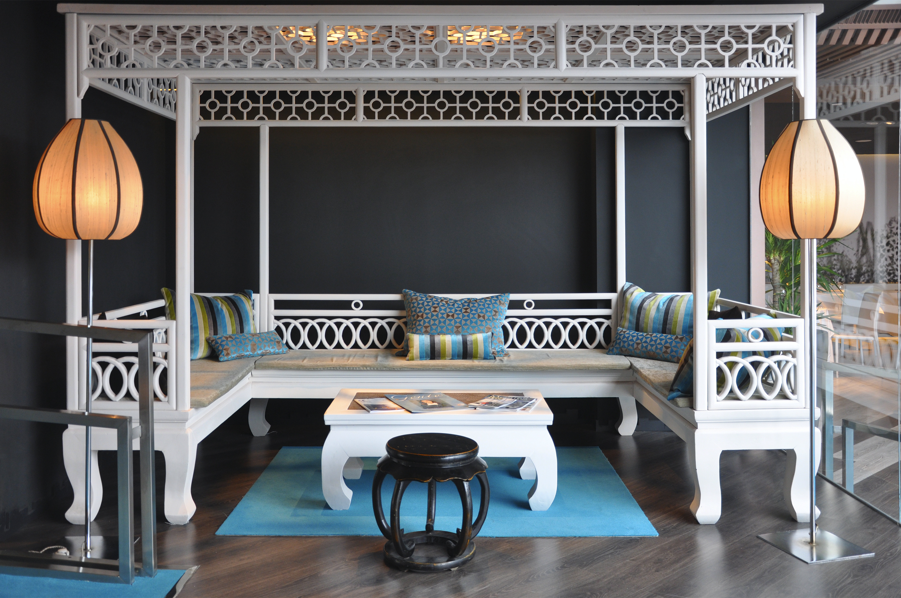 White gazebo lounge seating with blue cushions, intricate patterns, and floor lamps.