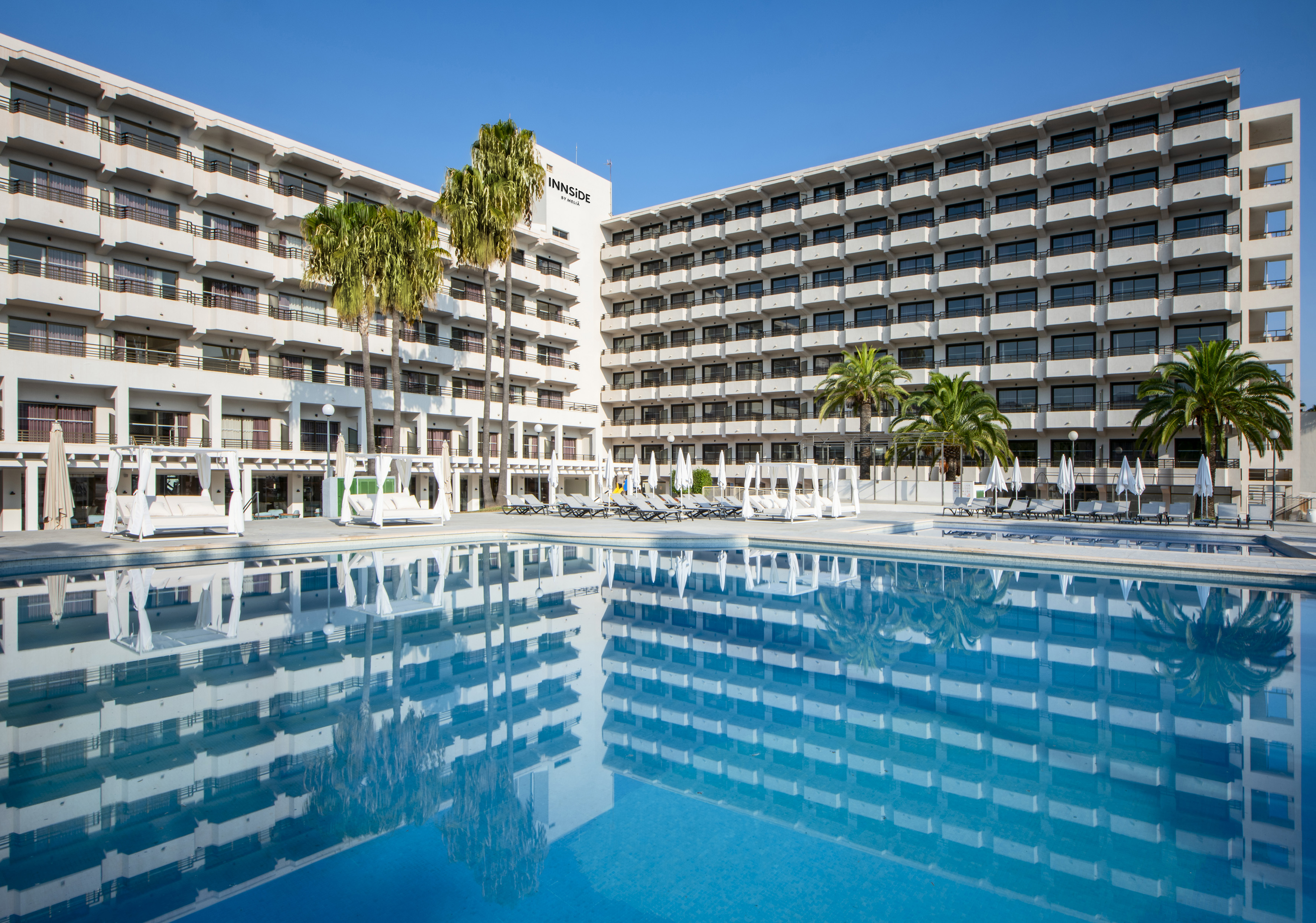 a pool with palm trees in front of a building