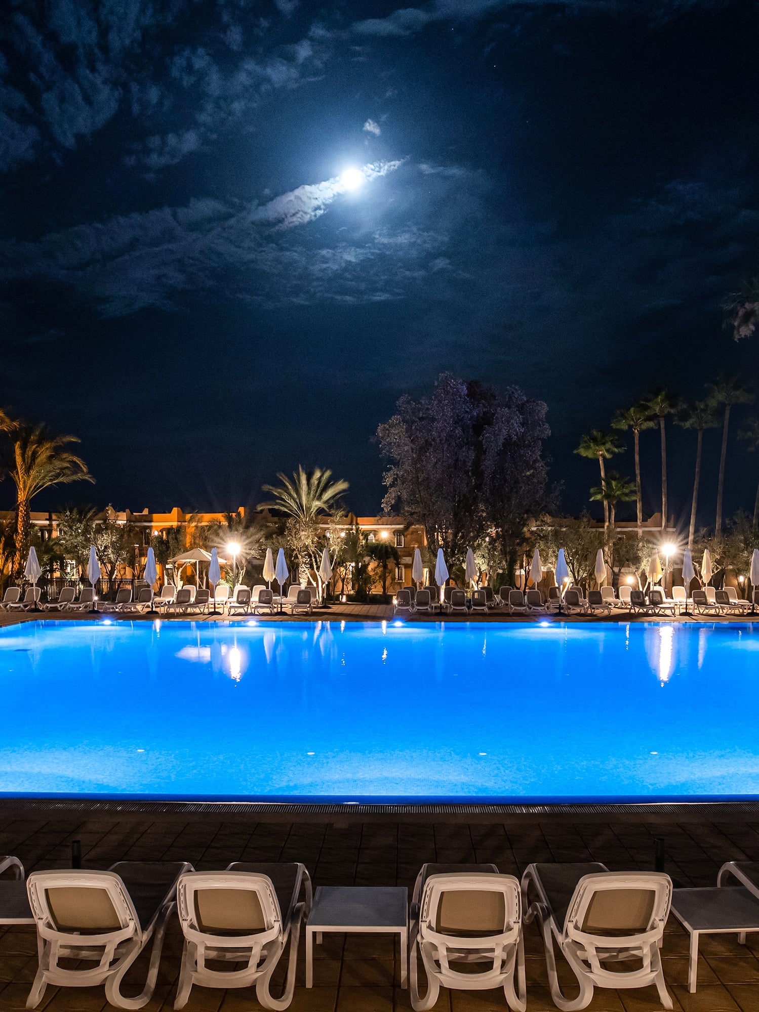 a pool with chairs and a building in the background