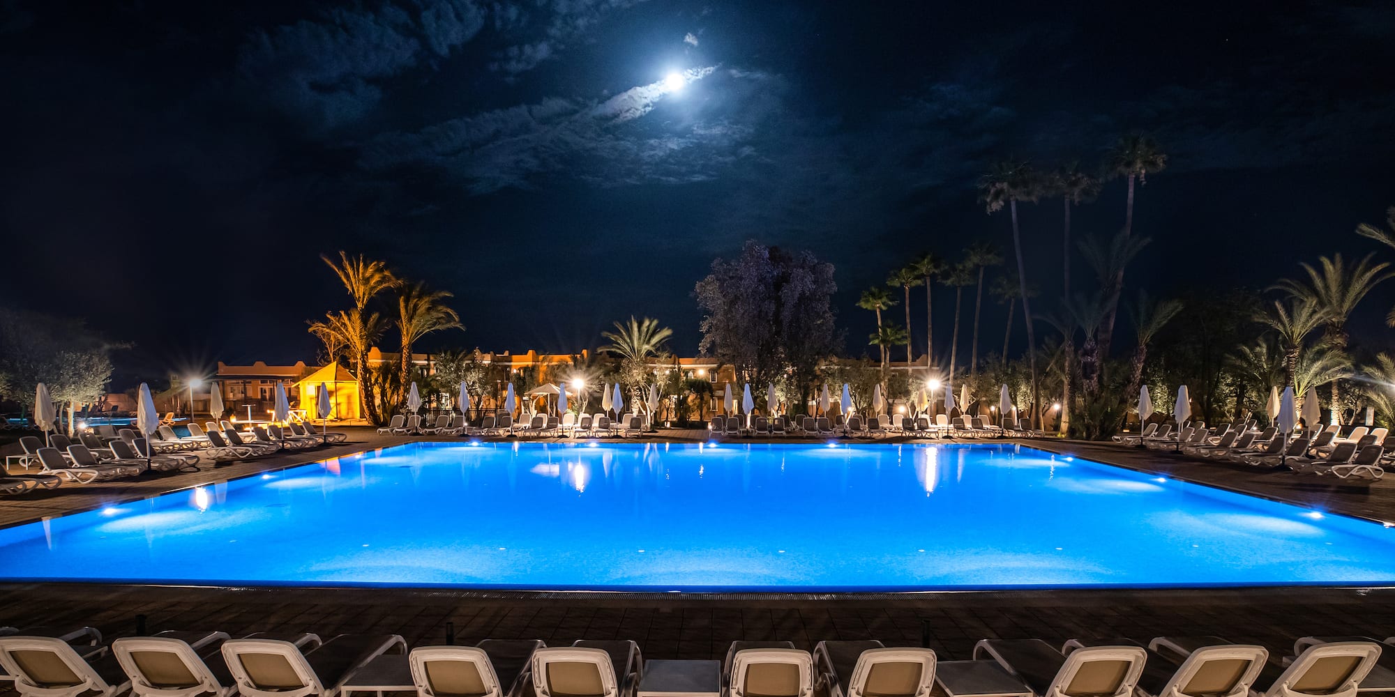 a pool with chairs and a building in the background