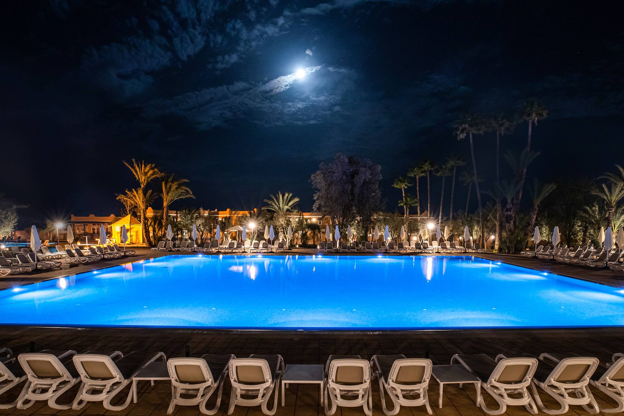 a pool with chairs and a building in the background
