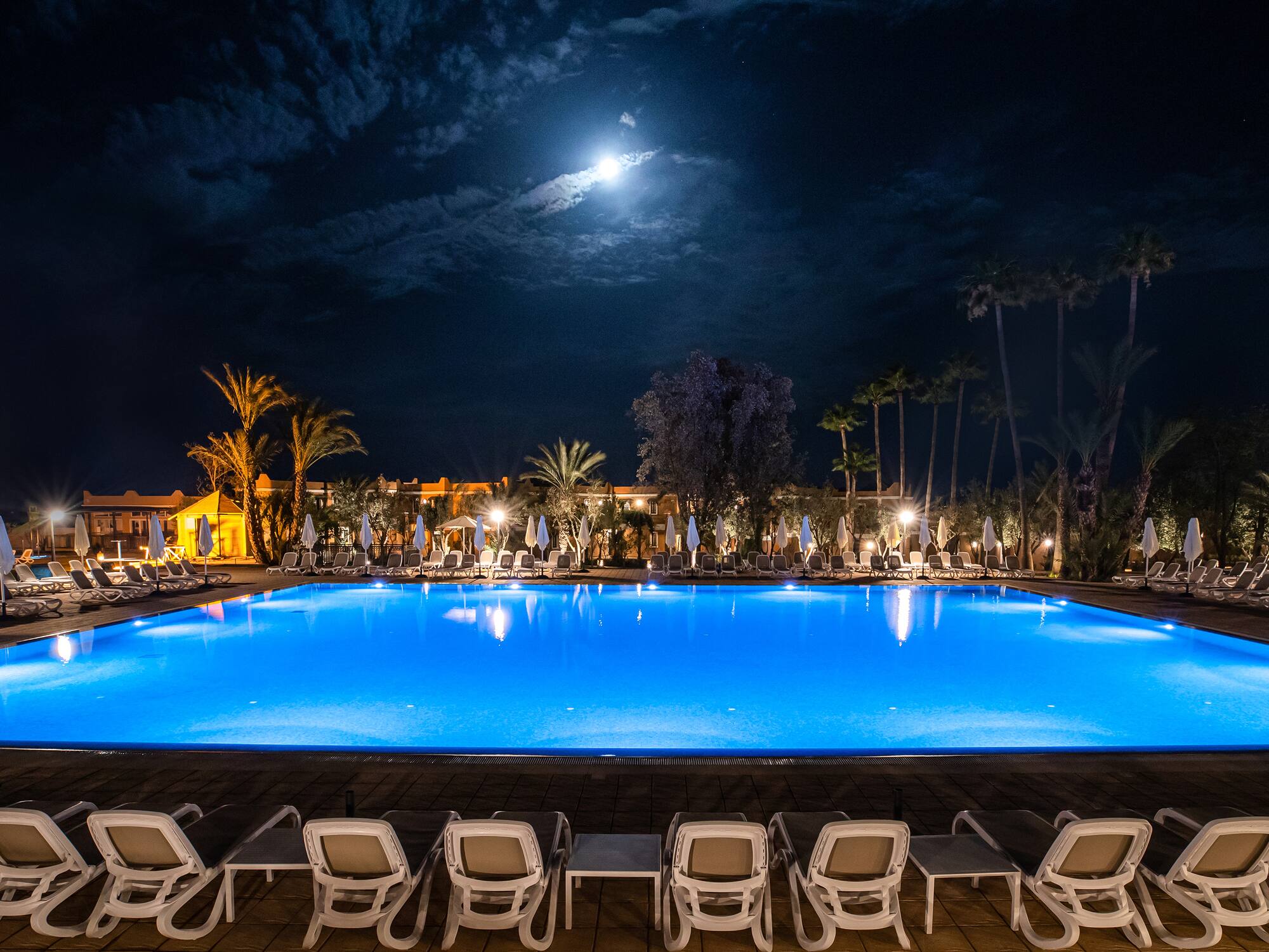 a pool with chairs and a building in the background