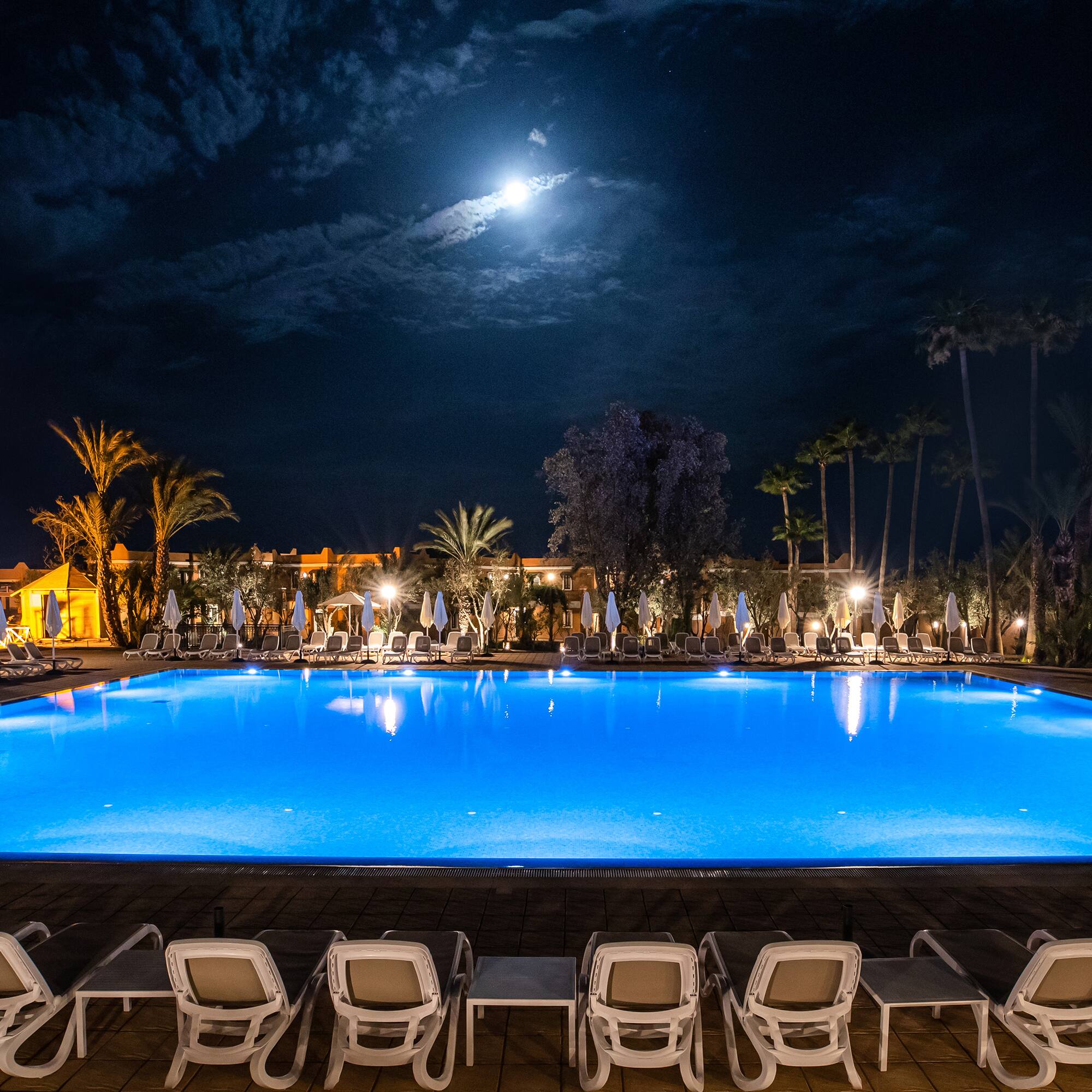 a pool with chairs and a building in the background